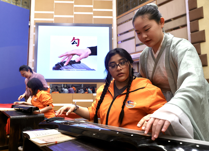 2024年3月20日,美国华盛顿州中学生代表团北京大学交流活动在北京大学英杰交流中心举行。图为来自华盛顿州的中学生体验古琴。